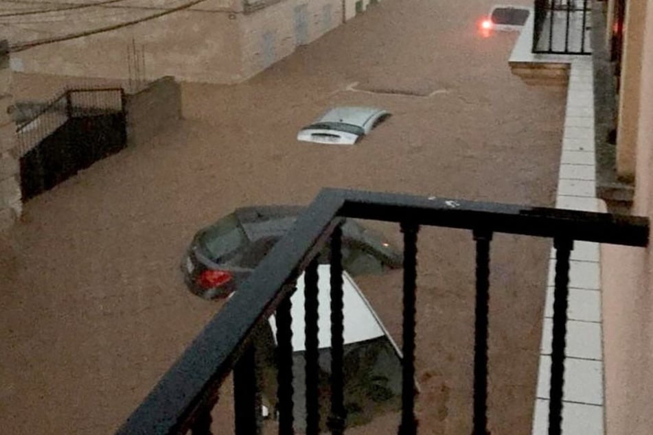 Die heftigen Wassermassen treiben die Autos vor sich her.