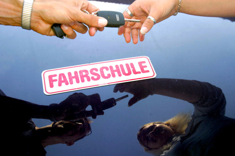 Ein Fahrlehrer überreicht seiner Fahrschülerin den Schlüssel zum Fahrzeug. Junge Menschen in Deutschlands Ballungsgebieten haben es mit dem Führerschein allerdings immer seltener eilig.
