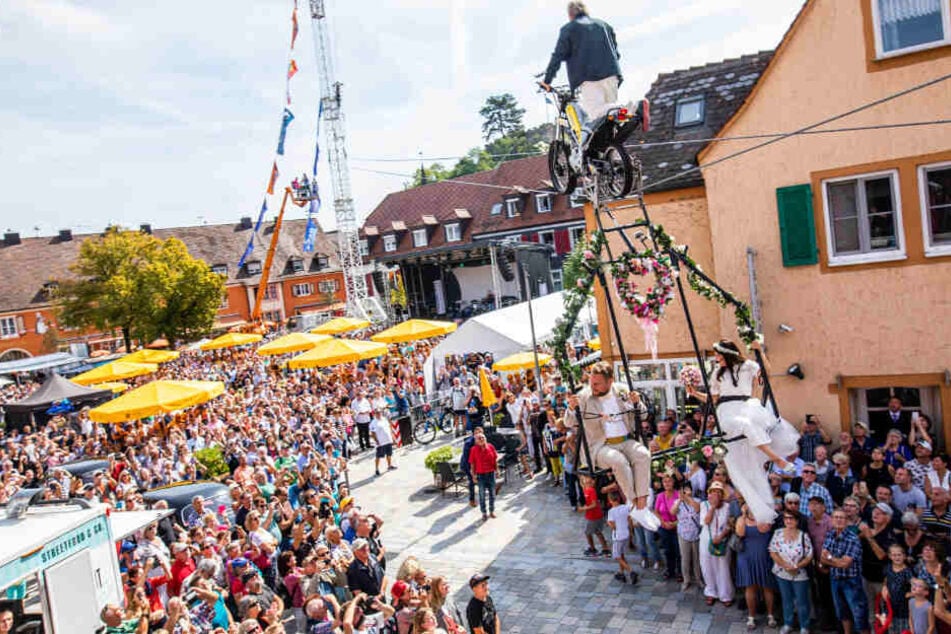 Bräutigam Sven Lier und Braut Anna Traber sitzen in einem Gestell, das mittels eines Motorrads auf einem Hochseil über den Breisacher Marktplatz gezogen wird.