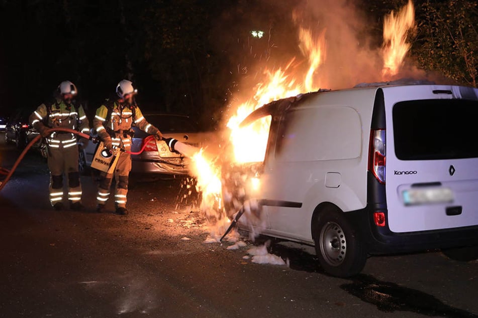 Feuerwehrleute löschen das brennende Auto.