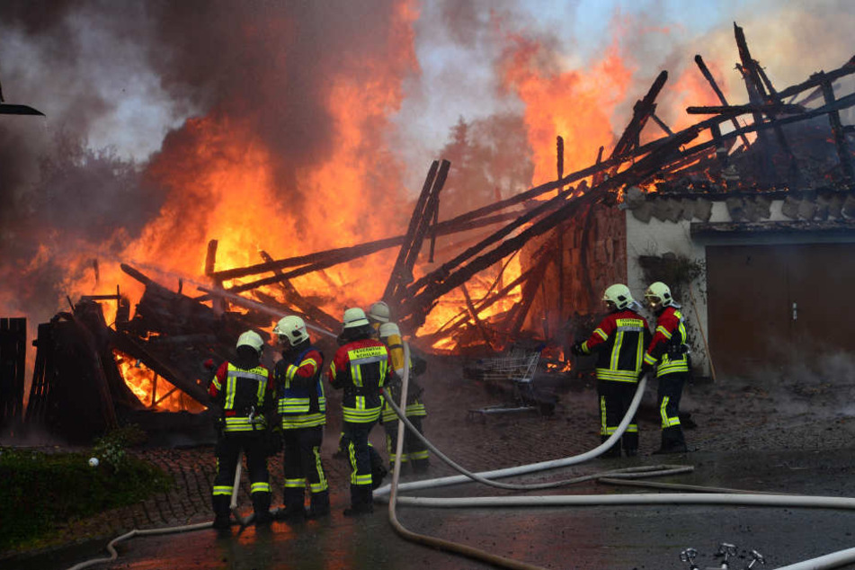 Feuerwehrmänner stehen vor dem ausgebrannten Gebäude.