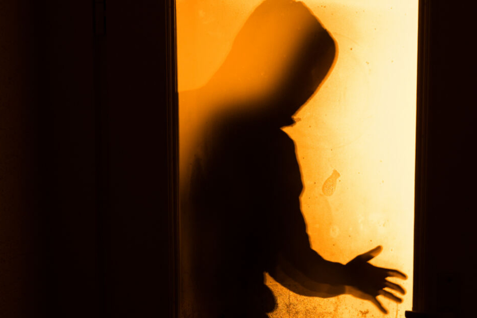 Der Schatten eines Mannes ist hinter einer Scheibe zu sehen.