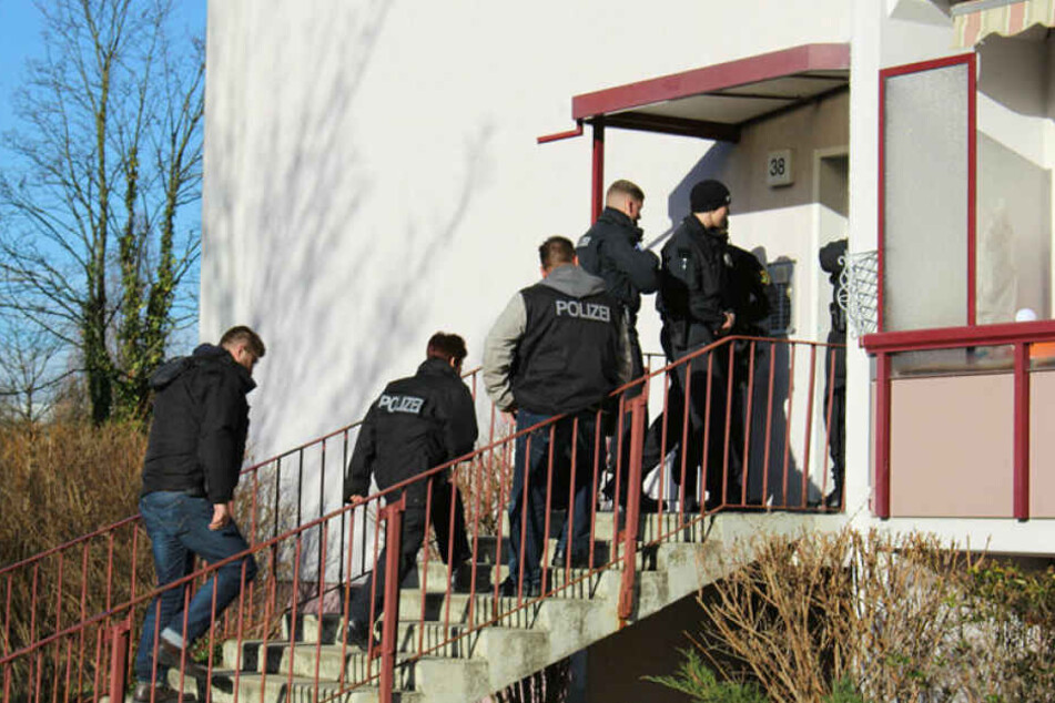 Polizisten stürmen am Morgen einen Plattenbau in Leipzig-Grünau. Eine Wohnung und der Keller werden durchsucht, danach mehrere Gegenstände beschlagnahmt.