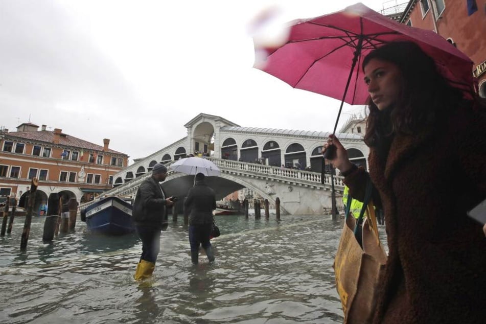Passanten gehen in der Nähe der Rialto-Brücke durch das Hochwasser. Die Flut erreichte um 10:35 Uhr einen Höchststand von 127 cm, während für den späteren Dienstagabend ein noch höheres Niveau von 140 cm prognostiziert wurde.