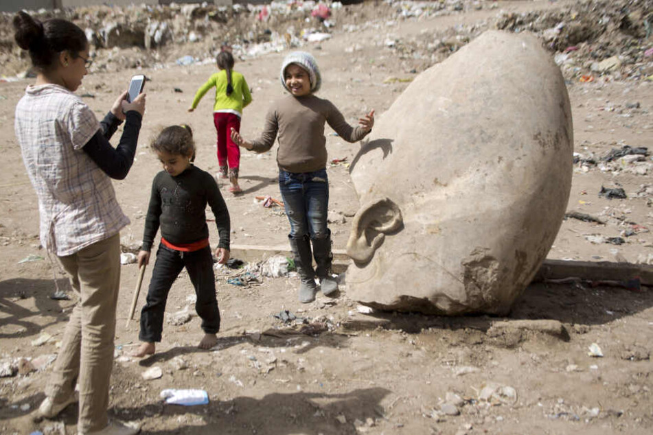 Der Koloss aus der Nachbarschaft: Kinder aus dem Wohngebiet in Kairo posieren
vor der entdeckten Statue