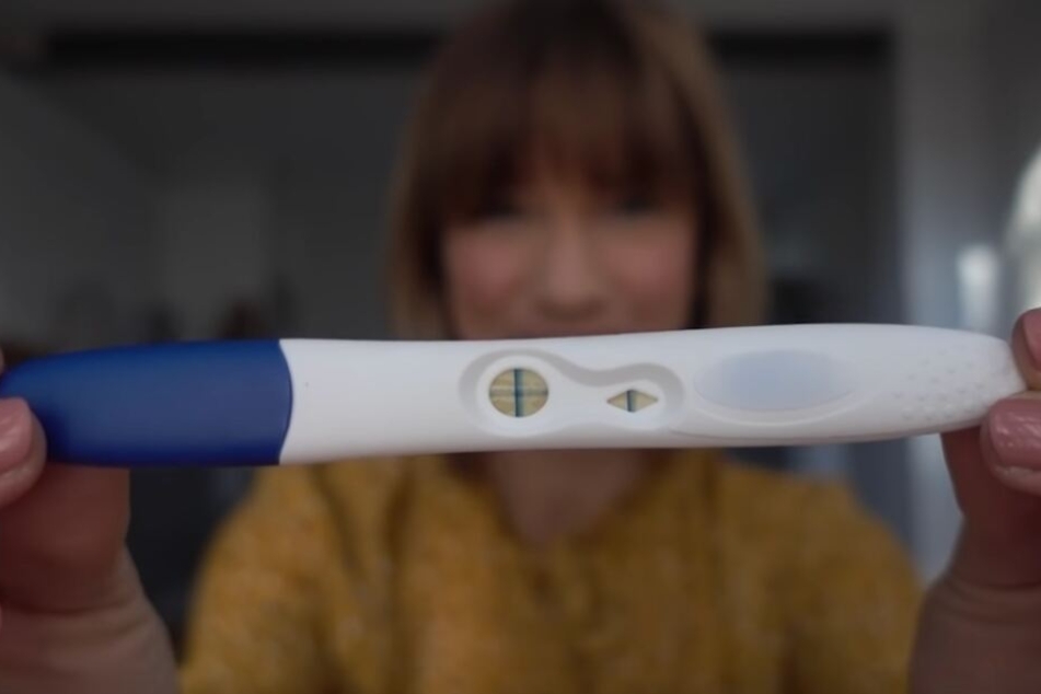 Stolz hält die werdende Mama den positiven Schwangerschaftstest in die Kamera.