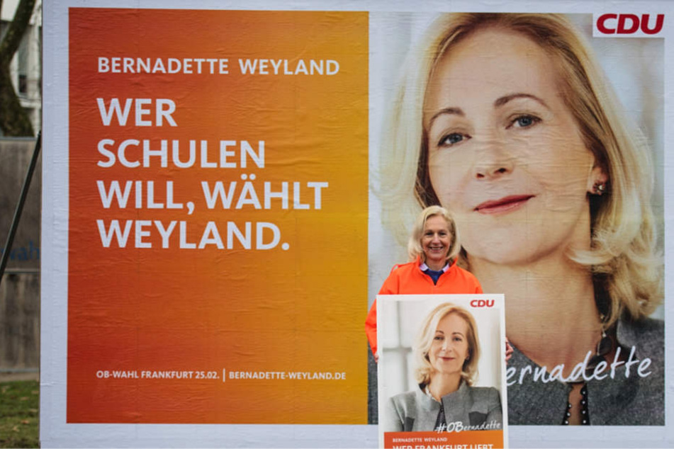 Die CDU-Kandidatin Bernadette Weyland steht vor ihrem Plakat zum Thema "Schulen".