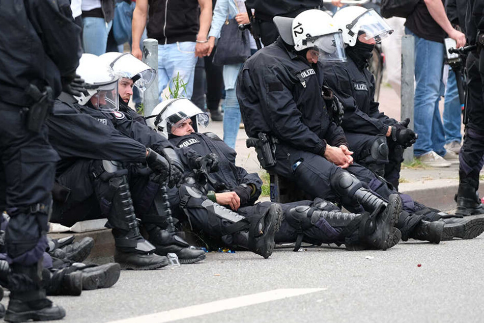 Völlig erschöpft sacken Polizisten zu Boden. Die tagelangen Ausschreitungen fordern ihren Tribut.