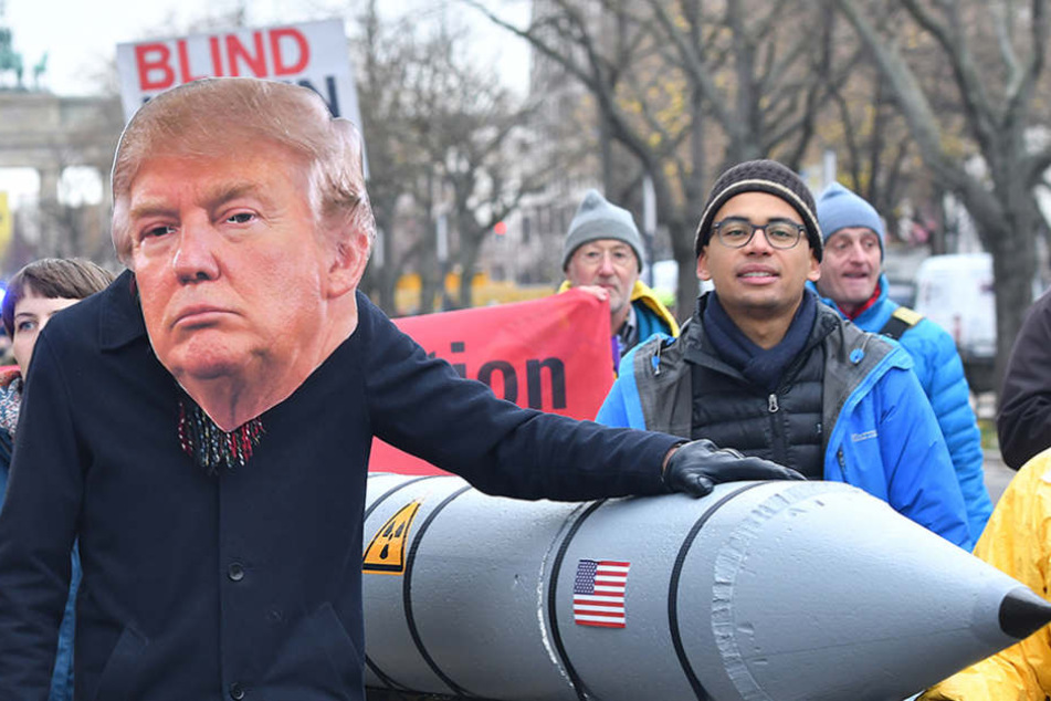 Ein Demonstrant mit der Maske des US-Präsidenten Donald Trump neben einer Raketen-Attrappe.