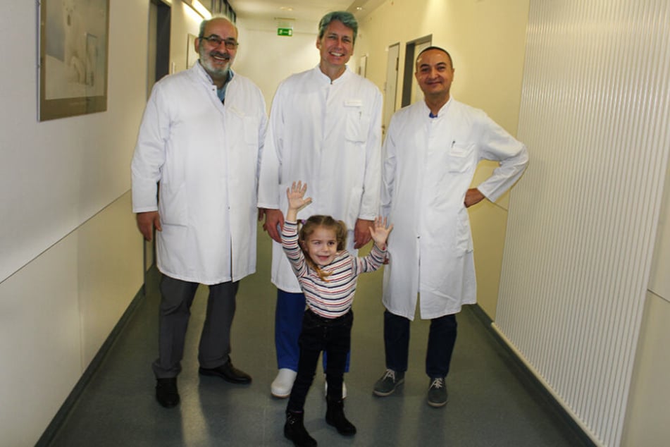 Die kleine Jara mit ihren Ärzten: (v.re.) Ph.D. Ahmed Shawky, Oberarzt für Wirbensäulenchirurgie, Dr. med. Ali Ezzati, Chefarzt der Wirbelsäulenchirurgie und Prof. Dr. med. Rüdiger Gerlach, Chefarzt der Neurochirurgie.