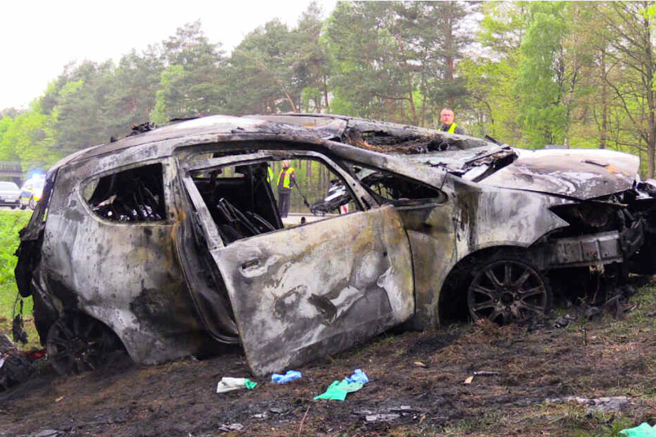 Das verbrannte Auto einer Frau steht nach einem Unfall an der A1. Dabei ist eine 68-Jährige tödlich verletzt worden. Drei weitere Menschen erlitten Verletzungen.