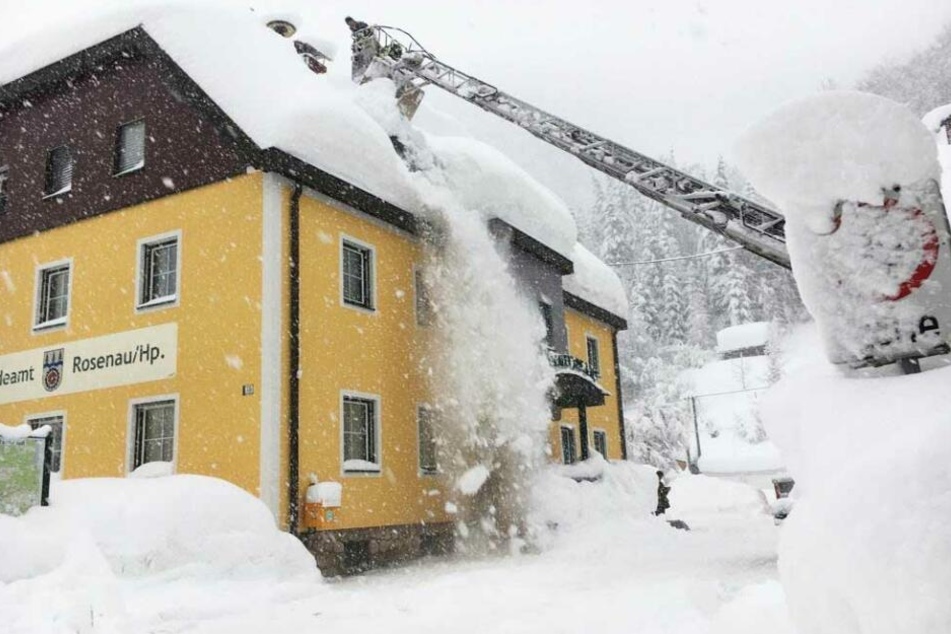 Feuerwehrkräfte räumen Schnee vom Dach eines Hauses in Kirchdorf an der Krems.