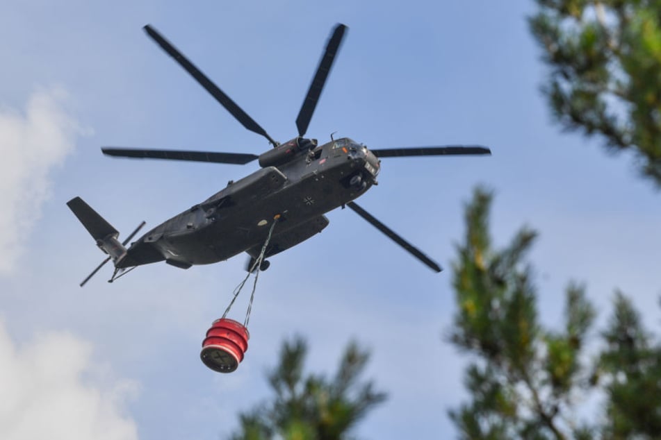 Ein Hubschrauber der Bundeswehr transportiert Löschwasser über dem ehemaligen Truppenübungsplatz in Südbrandenburg.
