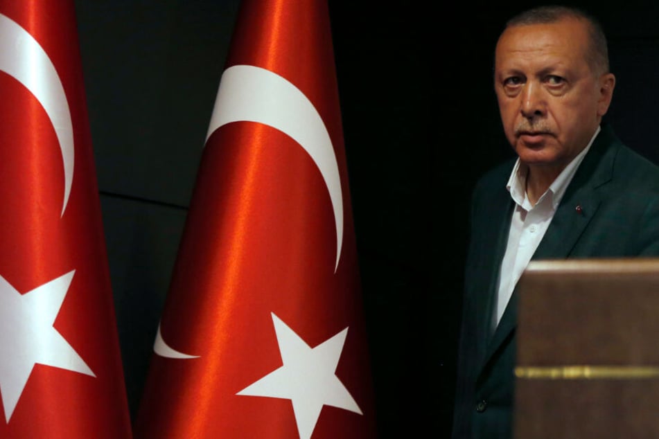 Der türkische Präsident Recep Tayyip Erdogan steht bei einer Pressekonferenz neben Flaggen der Türkei.