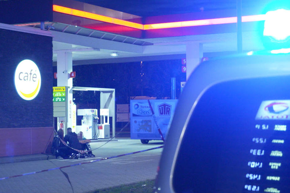 Die Polizei kümmert sich vor der Tankstelle um Zeugen des Raubüberfalls.