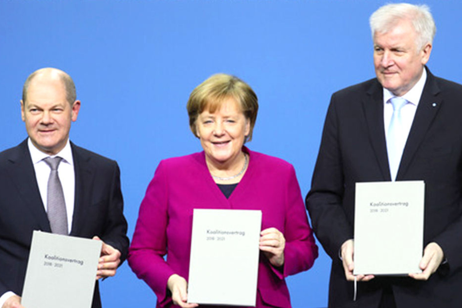 Bundeskanzlerin Angela Merkel (CDU), Mitte), der CSU-Vorsitzende Horst Seehofer (rechts) und der kommissarische SPD-Vorsitzende Olaf Scholz zeigen den unterzeichneten Koalitionsvertrag.