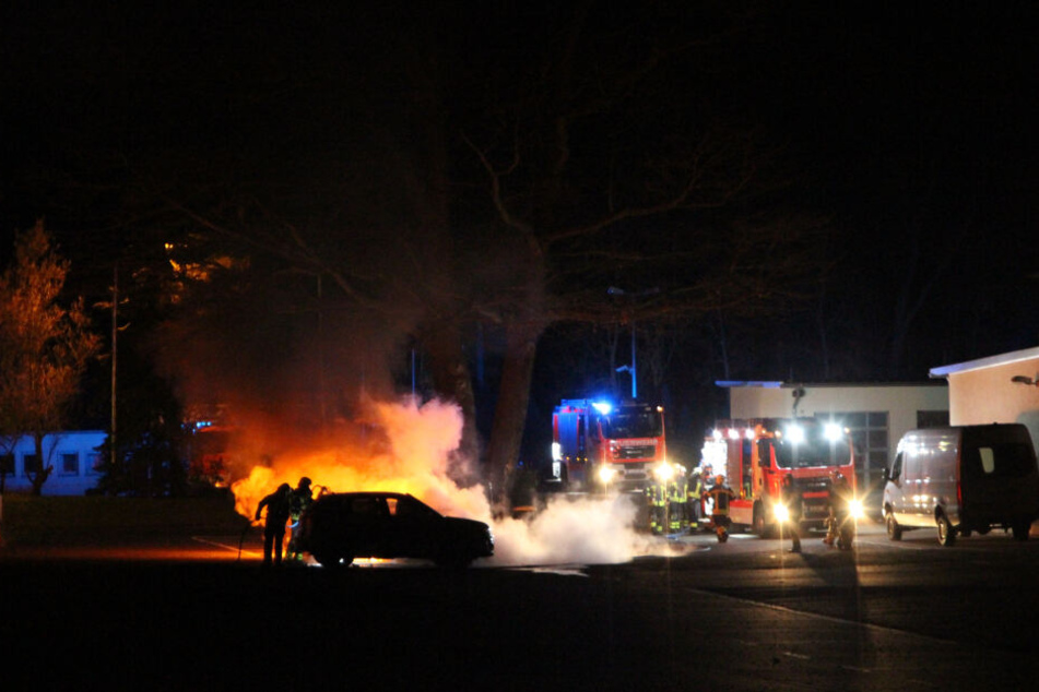 Feuerwehrleute löschen die ausgebrannten Fahrzeuge der städtischen Polizeibehörde. Zwei Autos brennen komplett aus, ein SUV wird schwer beschädigt. 