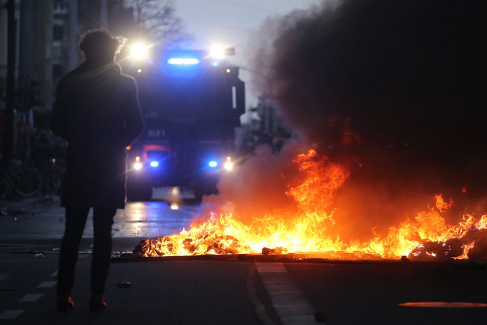 Ein Wasserwerfer steht am 12. Dezember 2015 vor einer brennenden Barrikade in Leipzigs Südvorstadt. Der Randale-Schaden ging damals in die Hunderttausende.