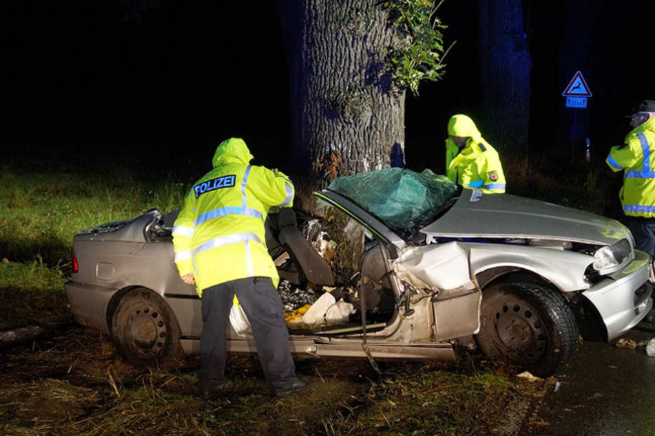 Polizeibeamte untersuchen in der Nacht das Wrack des verunglückten BMWs.