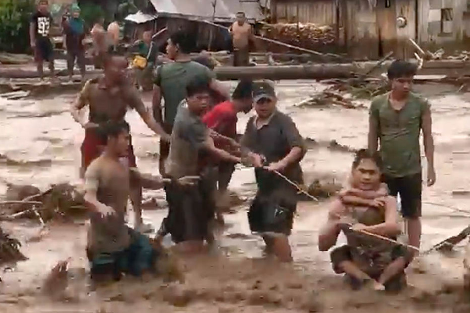Das Videostandbild zeigt Dorfbewohner, die am 22.12.2017 versuchen, in Lanao Del Norte über ein reißendes Hochwasser zu gelangen.