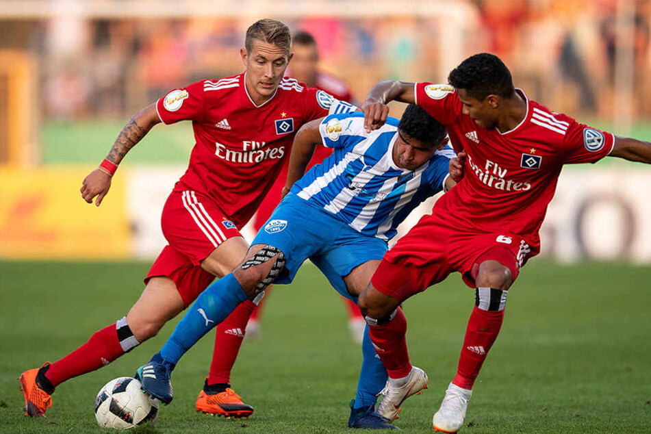Hamburgs Lewis Holtby (links) und Douglas Santos (rechts) kämpfen mit Erndtebrücks Murat-Kaan Yazar um den Ball.