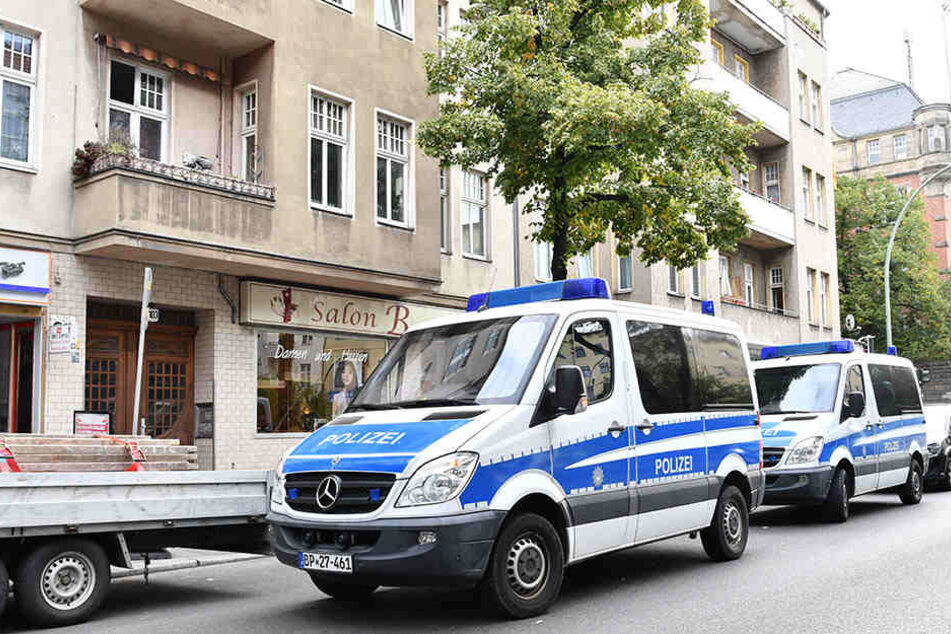Zwei Streifenwagen der Polizei warten während einer Razzia vor einem Haus. (Symbolbild)