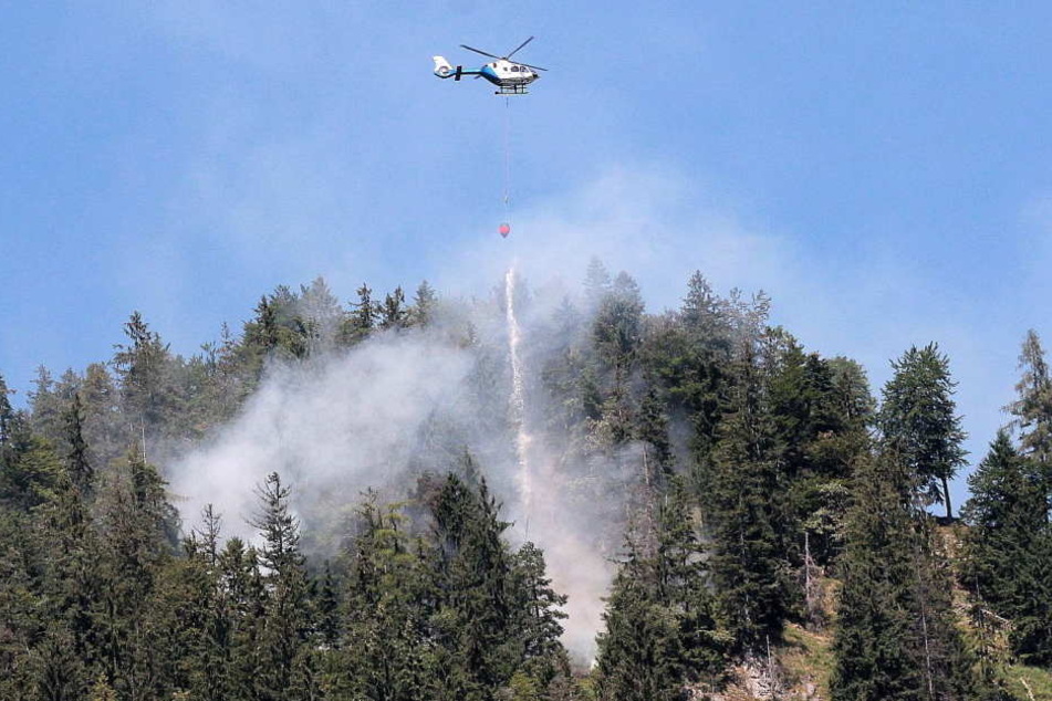 Feuerwehr und Polizeihubschrauber versuchen den Brand bei Oberaudorf unter Kontrolle zu bringen.