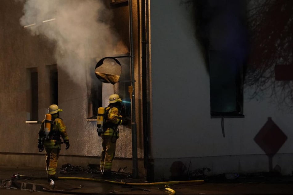 Zwei Feuerwehrmänner gehen vor Ort ihrer Arbeit nach.