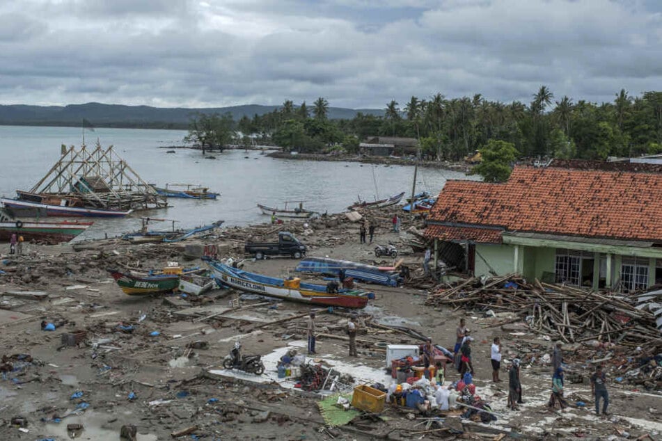 Menschen untersuchen die Schäden in einem von einem Tsunami getroffenen und verwüsteten Dorf.