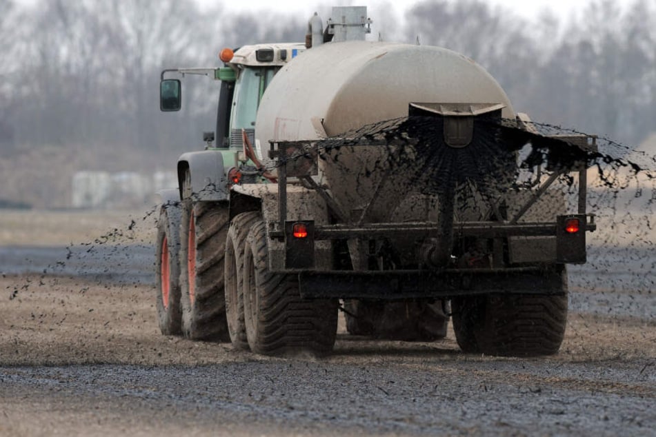 Mit einem Traktor wird ein Güllewagen über ein Feld gezogen: Die aufsteigenden Gase können für Menschen gefährlich werden.