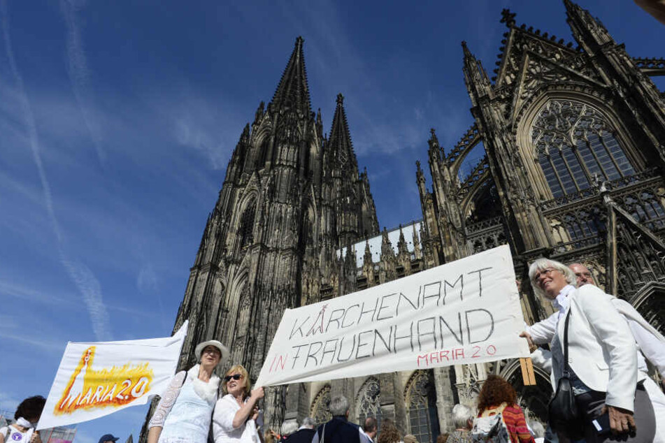 Demonstrantinnen der Bewegung "Maria 2.0" stehen mit einem Transparent mit der Aufschrift "Kirchenamt in Frauenhand - Maria 2.0" vor dem Kölner Dom.