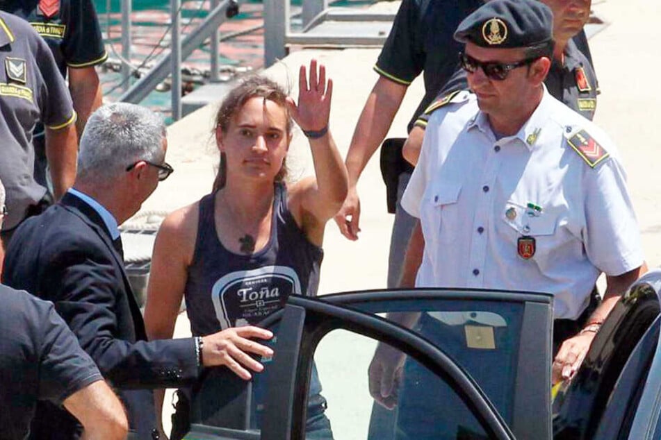 Italienische Polizisten nehmen Carola Rackete (Mitte) nach ihrer Ankunft im Hafen von Porto Empedocle mit.