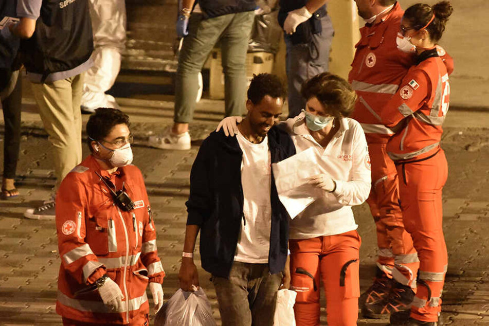 Ein Migrant spricht mit einer Helferin des Roten Kreuzes als er von Bord der "Diciotti" geht.