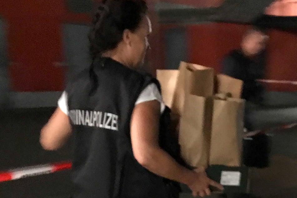 Eine Kriminalpolizistin trägt Beweismaterial vom Tatort weg.