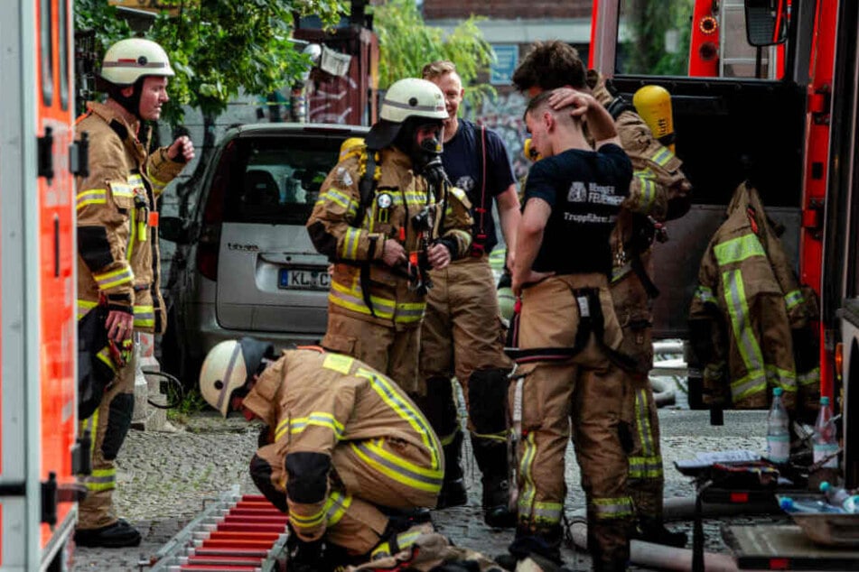 Feuerwehrmänner stehen nach dem Einsatz an der Straße Am Flutgraben in Kreuzberg.