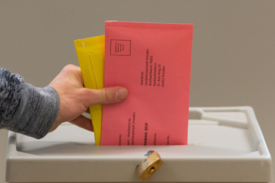 Ein Mann wirft im Wahllokal für die Briefwahl zwei Briefumschläge mit den Stimmzetteln für die Kommunalwahlen in Sachsen und die Europawahlen in eine Wahlurne.