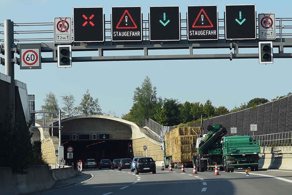 Ein mit Stroh beladener LKW und Einsatzfahrzeuge der Polizei stehen auf der A113. Der LKW war mit seiner Ladung im Tunnel stecken geblieben.