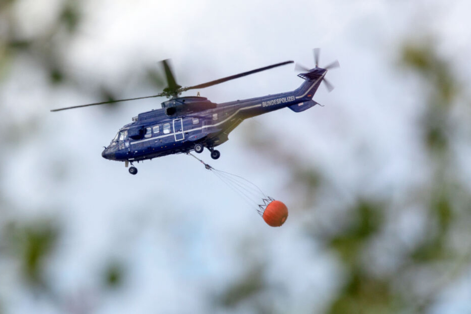 Ein Hubschrauber der Bundespolizei transportiert Löschwasser zum Brandherd.