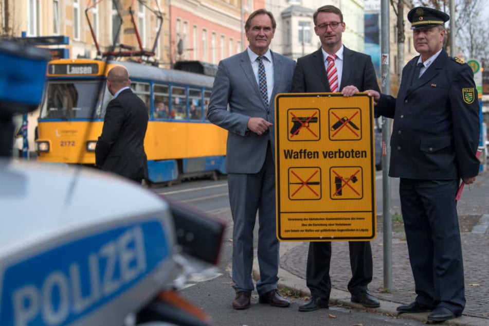 OB Burkhard Jung (SPD, v.l.), Innenminister Roland Wöller (CDU) und Polizeipräsident Bernd Merbitz zeigen auf der Eisenbahnstraße in Leipzig eines der neuen Hinweisschilder zur Waffenverbotszone.