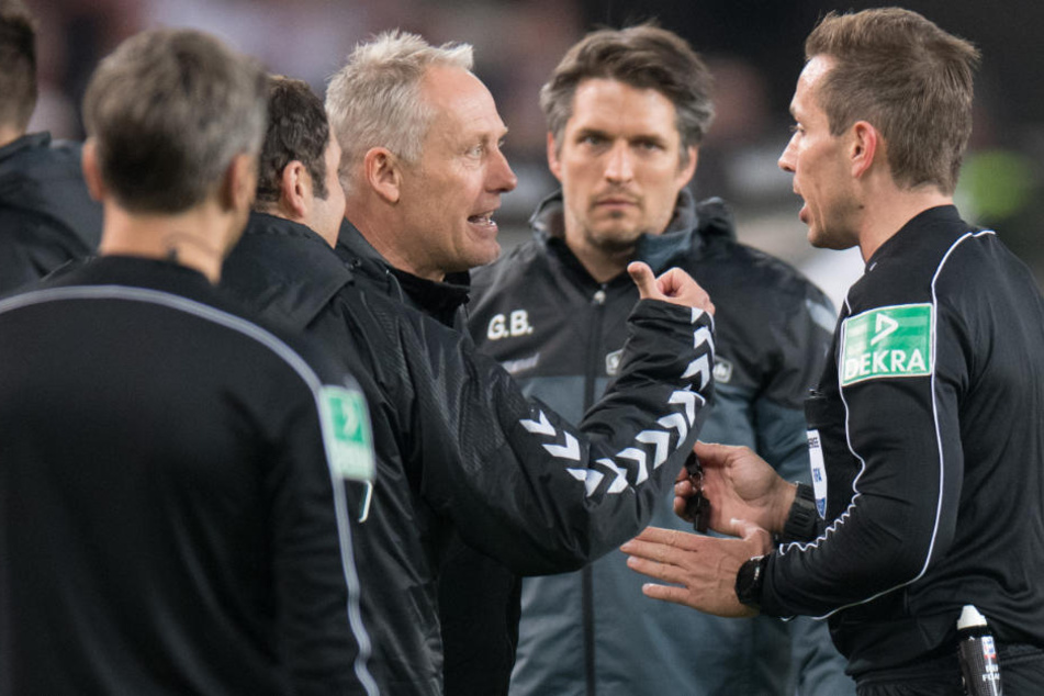 SC-Trainer Christian Streich (links) debattiert mit Schiedsrichter Tobias Stieler (rechts).