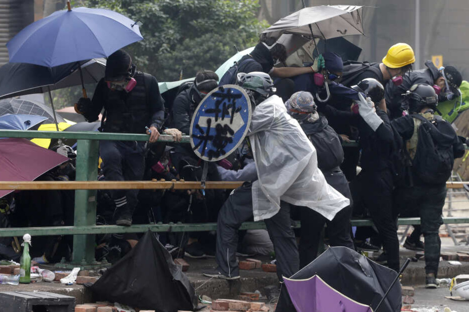 Demonstranten versuchen sich mit Regenschirmen zu schützen während Zusammenstößen mit der Bereitschaftspolizei