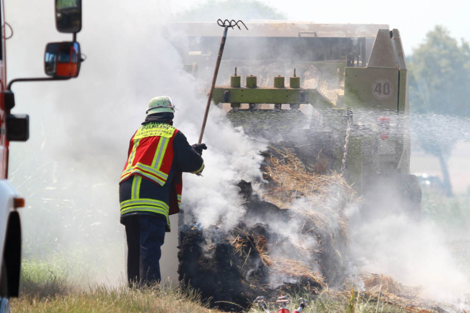 Ein Feuerwehrmann zerteilte das brennende Stroh mit einer Forke.