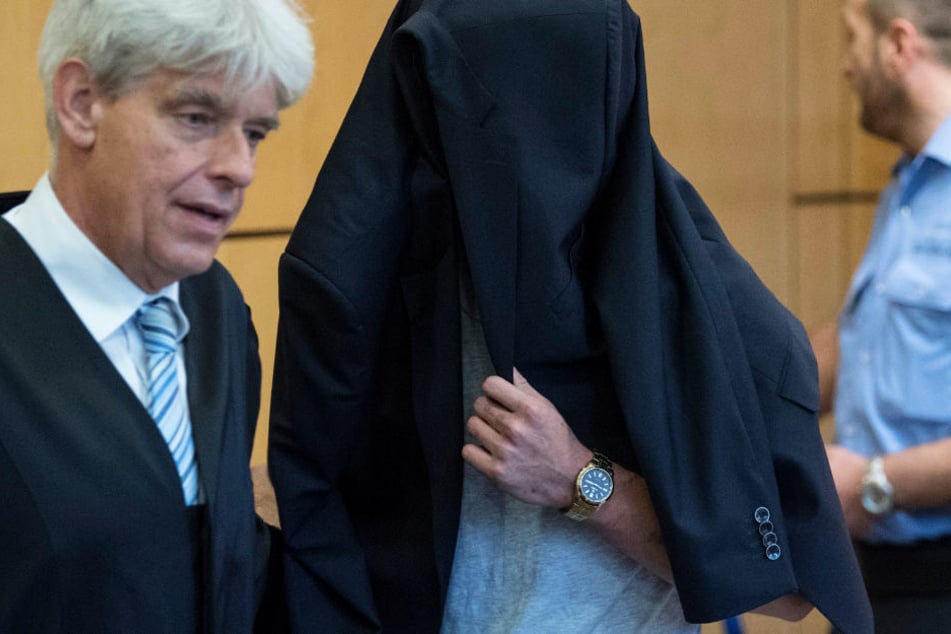 Verhüllt mit dem Jacket seines Verteidigers (l) betrat der Angeklagte den Verhandlungssaal.