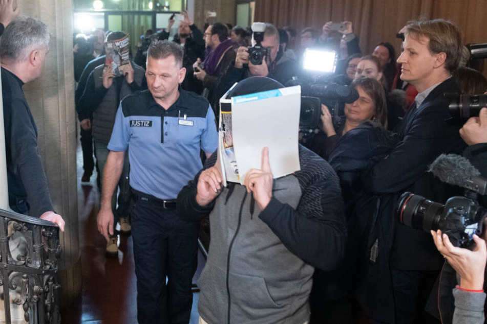 Einer von vier Angeklagten betritt beim Prozess-Beginn den Gerichtssaal.