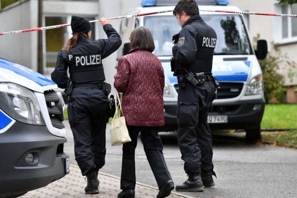 Polizisten begleiten eine Frau. Am Sonntagmittag wurden wieder Teile eines Wohngebiets abgesperrt.