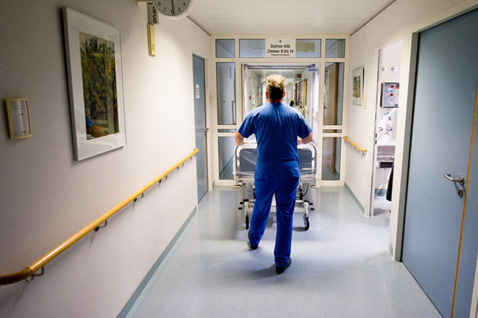 Ein Krankenpfleger schiebt einen Patienten auf die Station. (Symbolbild)