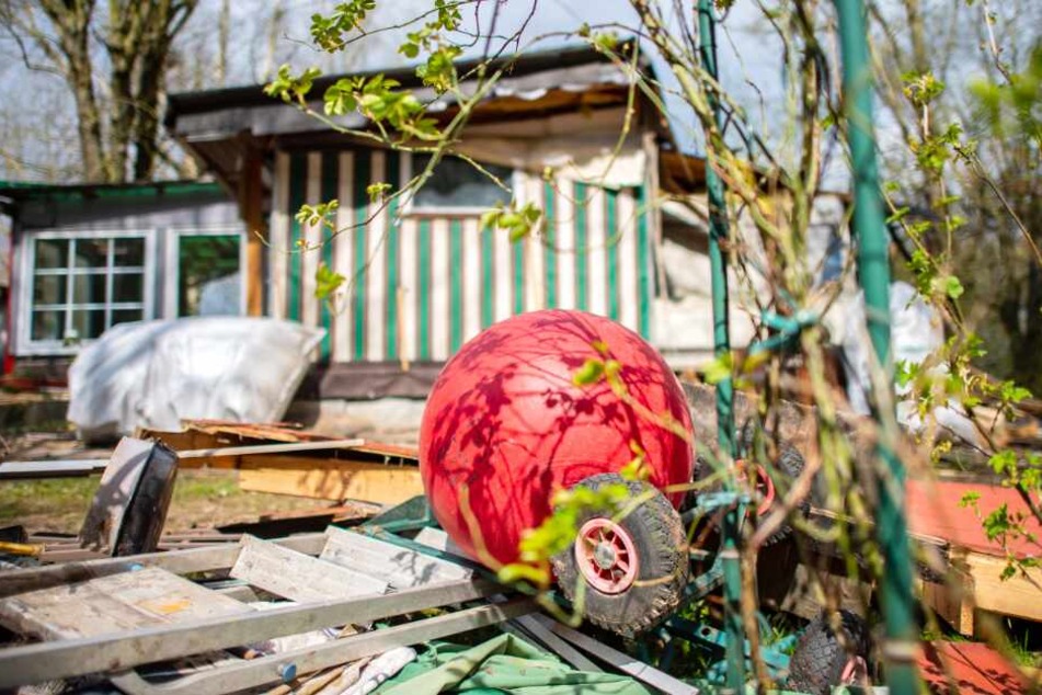 Ein Kindertretauto und ein Hüpfball liegen vor der bereits zum Teil abgerissenen Parzelle des mutmaßlichen Täters.