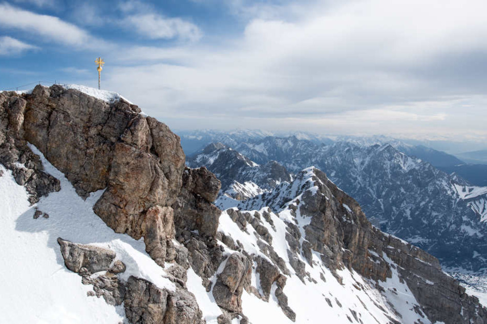 Die Sonne scheint im bayerischen Garmisch-Partenkirchen über dem Gipfelkreuz auf der Zugspitze.