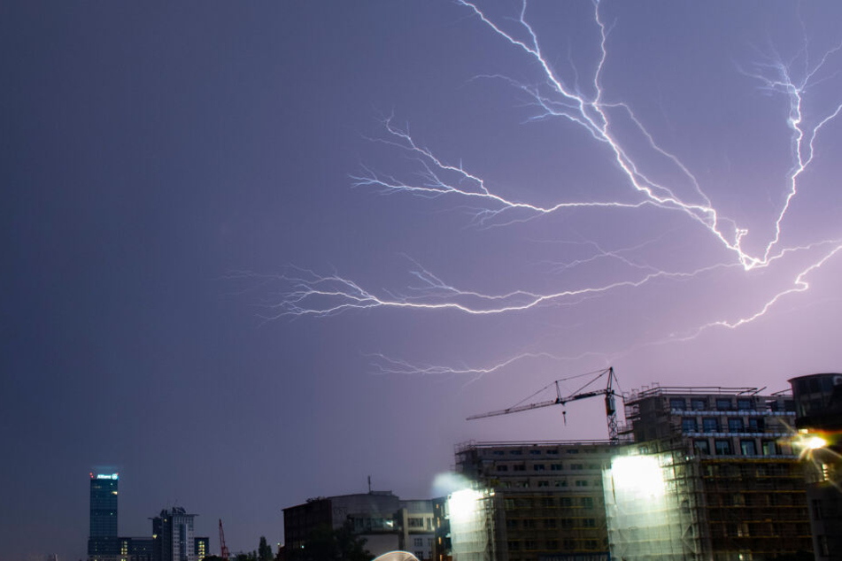Blitze zucken während eines Gewitters unweit des Allianz-Hochhauses in Berlin über den Himmel.
