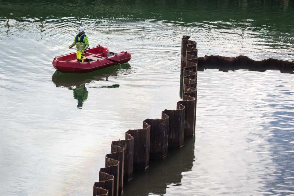 Ein Mitarbeiter einer Spezialfirma für Unterwasserarbeiten schippert über die mit Grundwasser vollgelaufenen Baugrube.